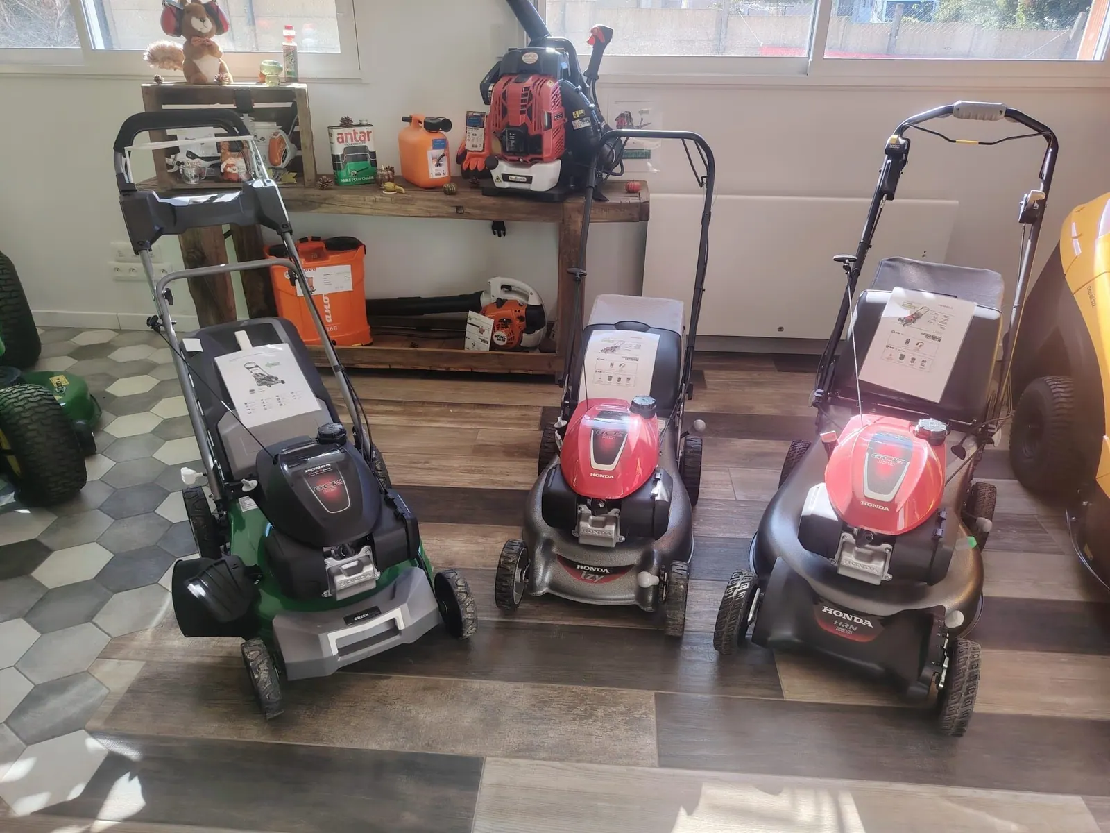 Le pôle tondeuses du magasin : trois tondeuses Honda devant l’établi